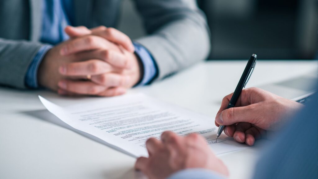 A man signing a legal contract in front of a lawyer