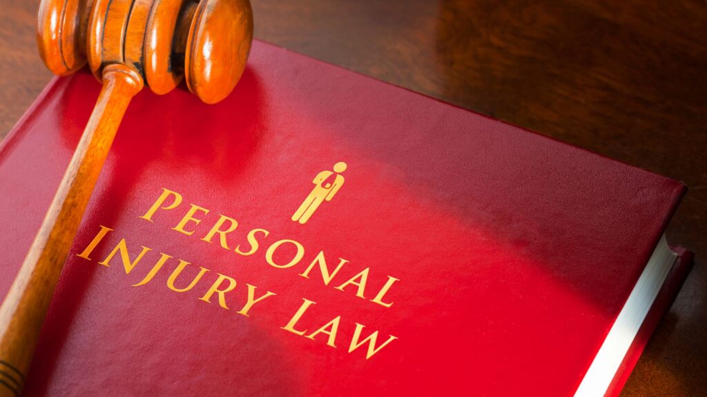Personal injury law book next to a gavel on a lawyer's desk